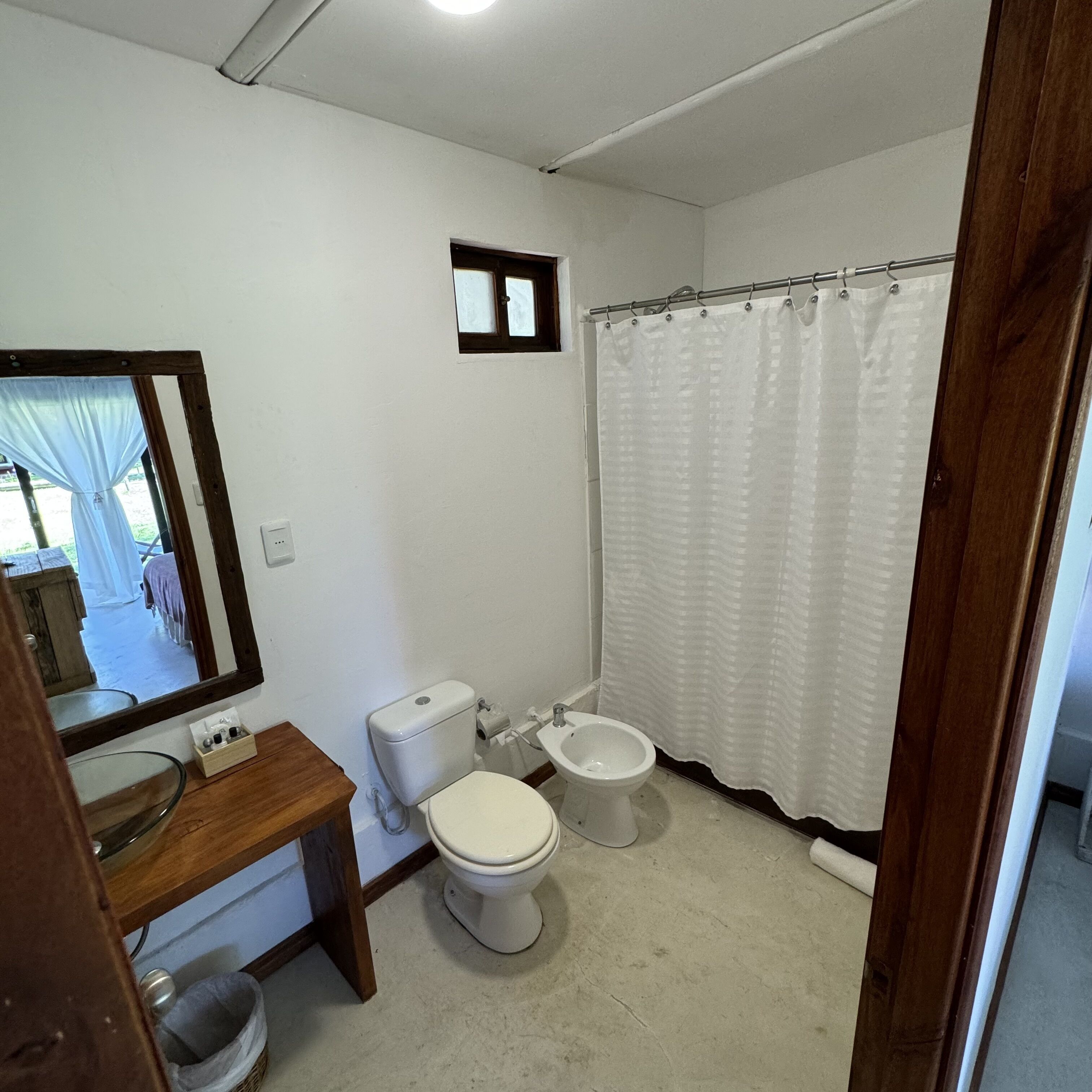 Un baño pequeño y limpio con inodoro, bidé y espejo.