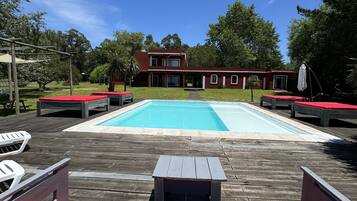 Una piscina al aire libre, sombrillas, sillones reclinables de piscina