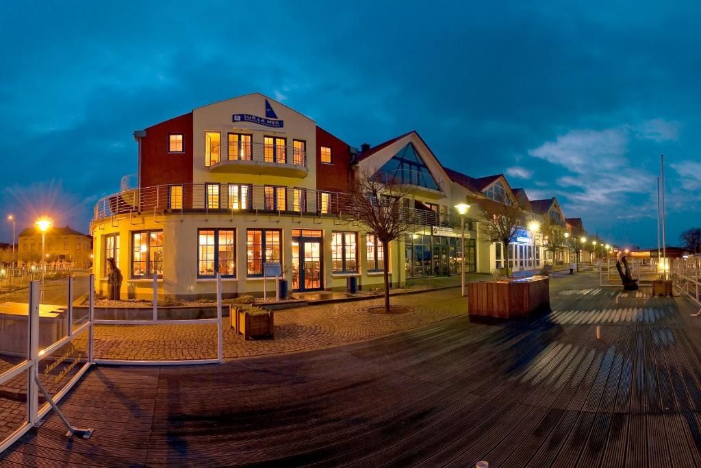 A waterfront hotel with a prominent building, a boardwalk, and outdoor seating.