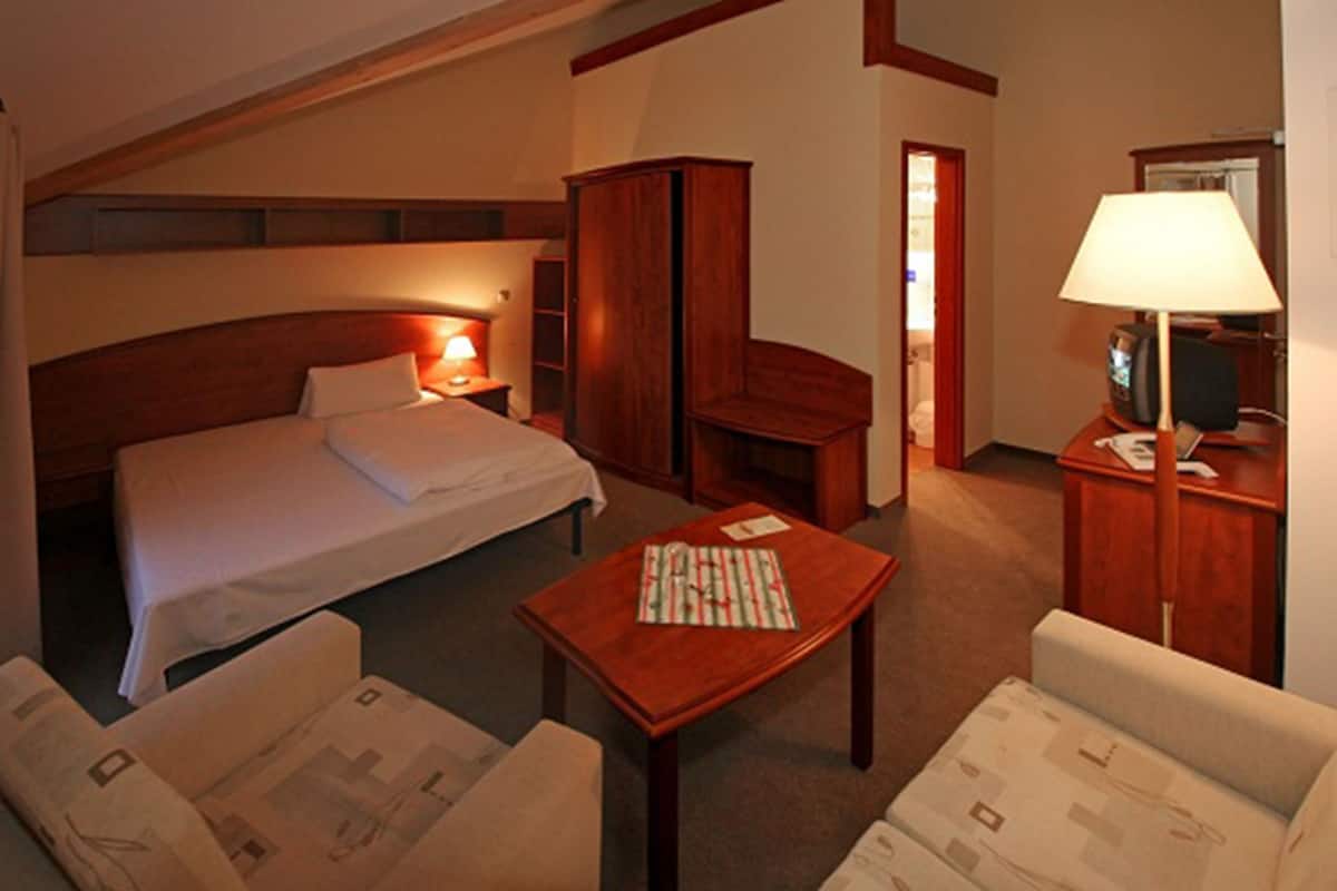 Une chambre d’hôtel comprenant un lit, un bureau, une chaise, une petite table et un placard.