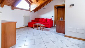 A room with a sloped ceiling, a red sofa, a wooden table, and a radiator. - Barcaiolo Apartment (Lecco)