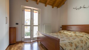 A bedroom with a wooden bed, a radiator, and a door leading to an outdoor area. - Barcaiolo Apartment (Lecco)