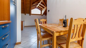 A dining area with a wooden table and chairs, a bottle of wine, and a window with a wooden roof. - Barcaiolo Apartment (Lecco)