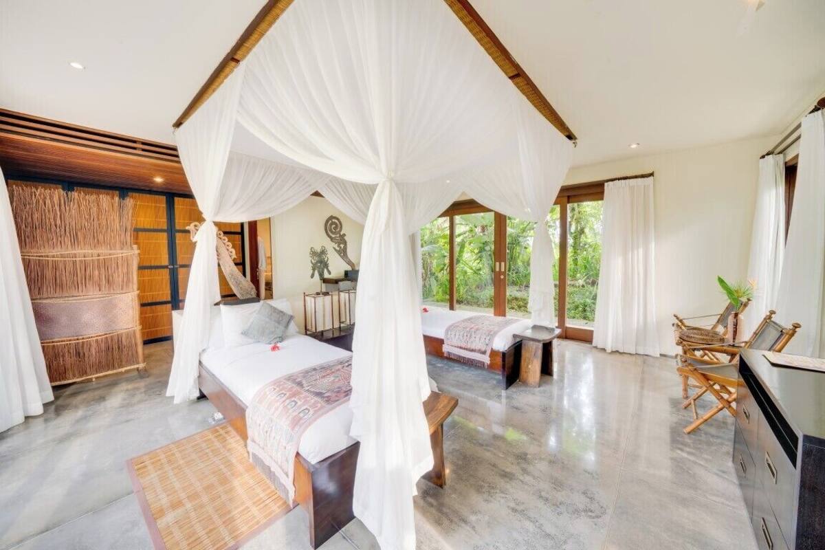 A bedroom with a canopy bed, a sitting area with a bench, and a TV.