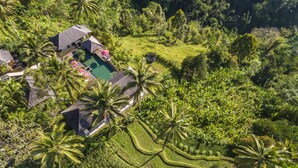 An aerial view of a resort with multiple buildings, a swimming pool, and lush tropical vegetation. - Awan Putih Resort (Kerta)