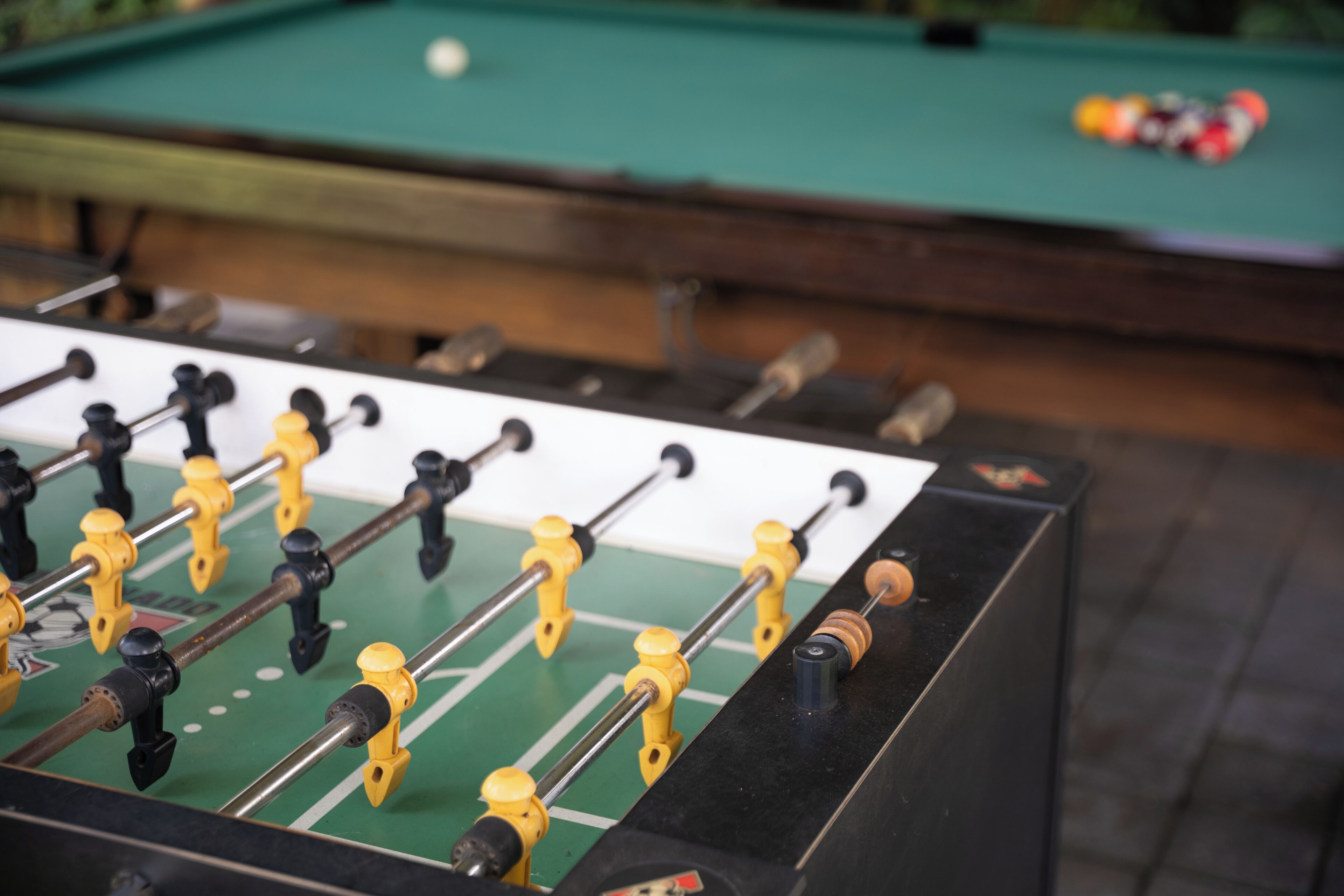 Una mesa de fútbol de mesa con superficie verde y barras de metal con manijas amarillas.