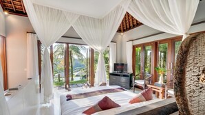 A spacious bedroom with a large bed, a desk, and a TV. - Awan Putih Resort (Kerta)