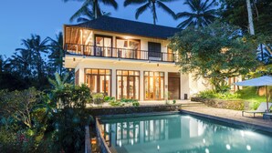 A two-story house with a swimming pool, surrounded by lush greenery and palm trees. - Awan Putih Resort (Kerta)