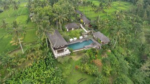 A resort with a pool, thatched-roof structures, and lush greenery. - Awan Putih Resort (Kerta)