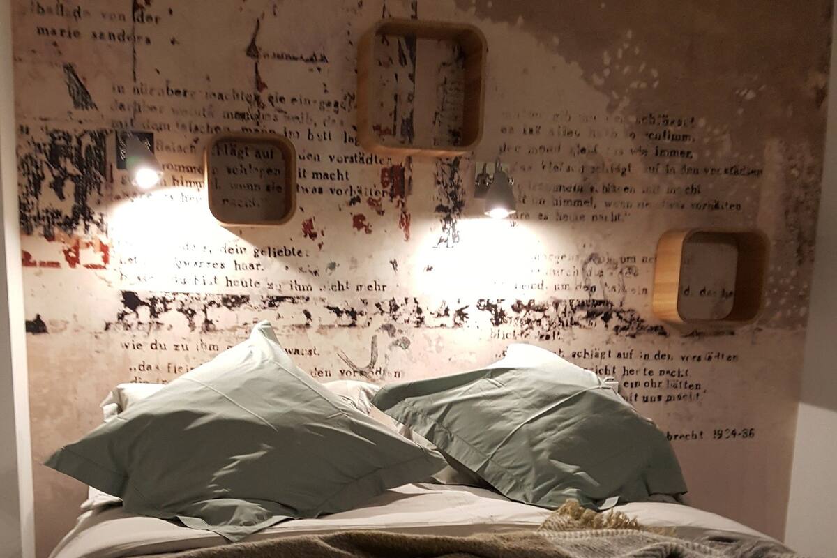 A bedroom with a bed, pillows, and a wall with text and a clock.