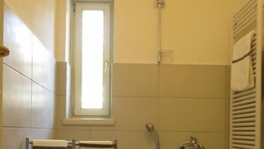 A small bathroom with a bathtub, toilet, and a window. - Appartamento Don Abbondio (Lecco)