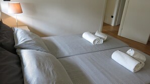 A neatly made bed with striped bedding and rolled towels on the side. - Appartamento Don Abbondio (Lecco)