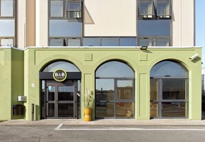 Et B&B hotel med grøn facade, store vinduer og en tydelig indgang.