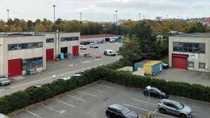 A parking lot with several cars and a building with red doors. - B&B HOTEL Paris Vitry-sur-Seine 3 étoiles (Vitry-sur-Seine)