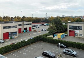 Un estacionamiento con varios coches y un edificio con puertas rojas.