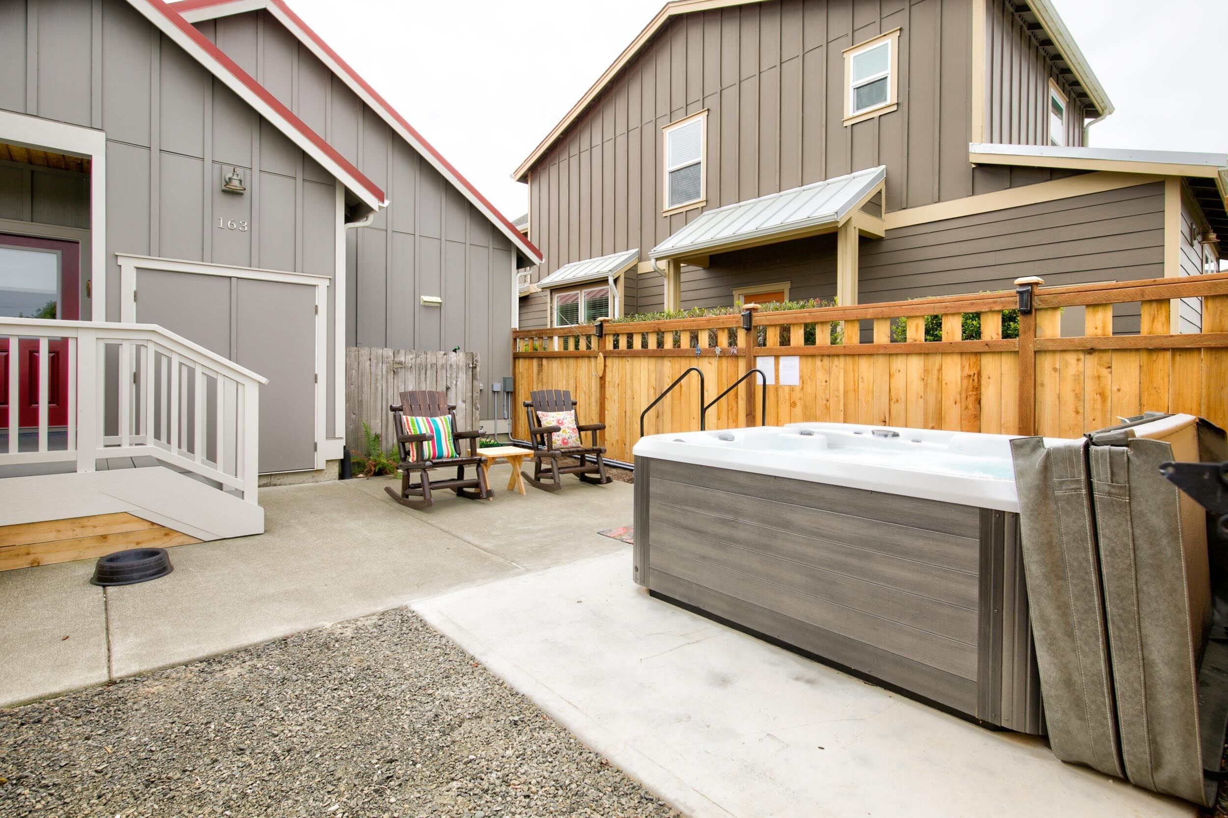 Ein Wohngebiet mit Holzzaun, Whirlpool und kleiner Terrasse mit Geländer.