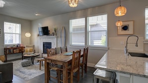 Una cocina moderna con comedor, que incluye chimenea, mesa de comedor de madera y ventanas amplias.