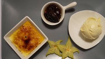 Ein Dessertteller mit Crème brûlée, einer kleinen Marmeladenschale und einer Kugel Eis.