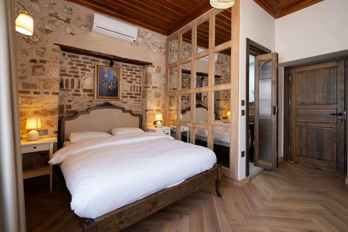 A bedroom with a wooden bed, stone walls, and a large mirror.