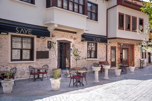 A building with 'SAVE' signage, outdoor seating with chairs and tables, and potted plants. - Saye Konak Kaleiçi&Oldtown (Antalya)