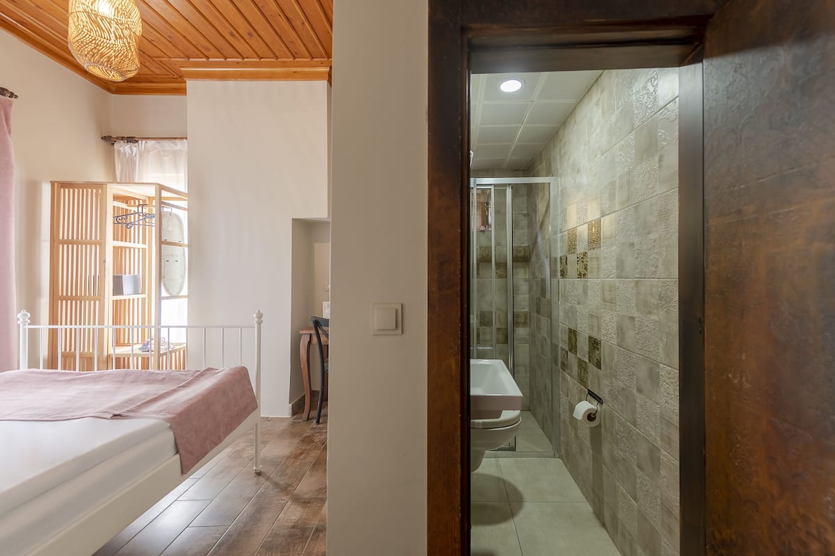 A bedroom with a bed, a wooden ceiling, and a window with a curtain.