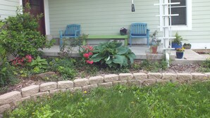 A porch with two blue chairs, a green bench, and potted plants. - Montrose Farms Alpaca Ranch (Brownsburg)