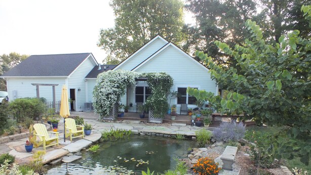 A house with a garden, including a pond, potted plants, and outdoor furniture. - Montrose Farms Alpaca Ranch (Brownsburg)
