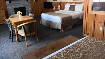 Habitación de hotel con cama, televisor, chimenea y zona de comedor con mesa y sillas.