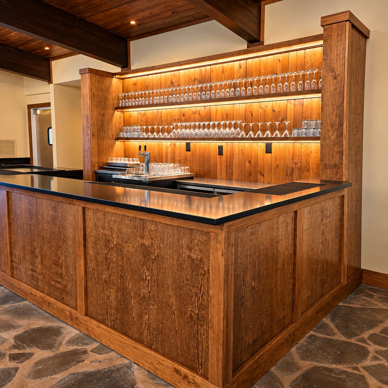 A bar area with a wooden counter and a shelf of glasses.