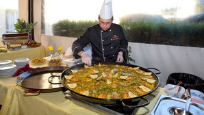 A chef preparing a large seafood paella on a table with plates and utensils. - Interpass Golf Playa Country Club (Isla Cristina)