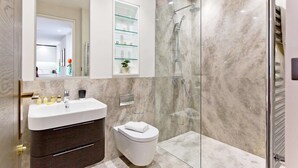 Un bagno moderno con doccia in marmo, specchiera con ante in vetro e lavandino bianco.