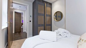 Una camera d'albergo con un letto, uno specchio e un ingresso che dà su un bagno.