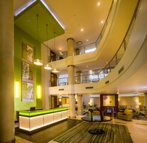 Un vestíbulo de hotel con una recepción, varios pisos y un atrio central.