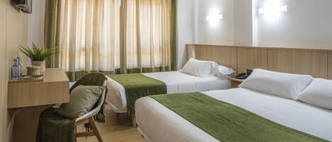 Habitación de hotel con dos camas, un escritorio, una silla y un televisor.