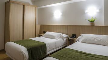 A hotel room with two beds, a wardrobe, bedside tables with lamps, and a wall-mounted light fixture.