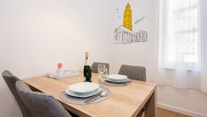 A dining table set with plates, a bottle, and a glass, with a wall decoration of a tower and a building. - Lugo Apartments (Split)