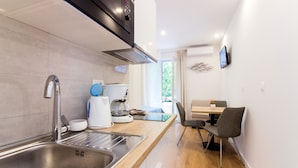 A modern kitchen with a stainless steel sink, a coffee maker, and a dining area with a table and chairs. - Lugo Apartments (Split)