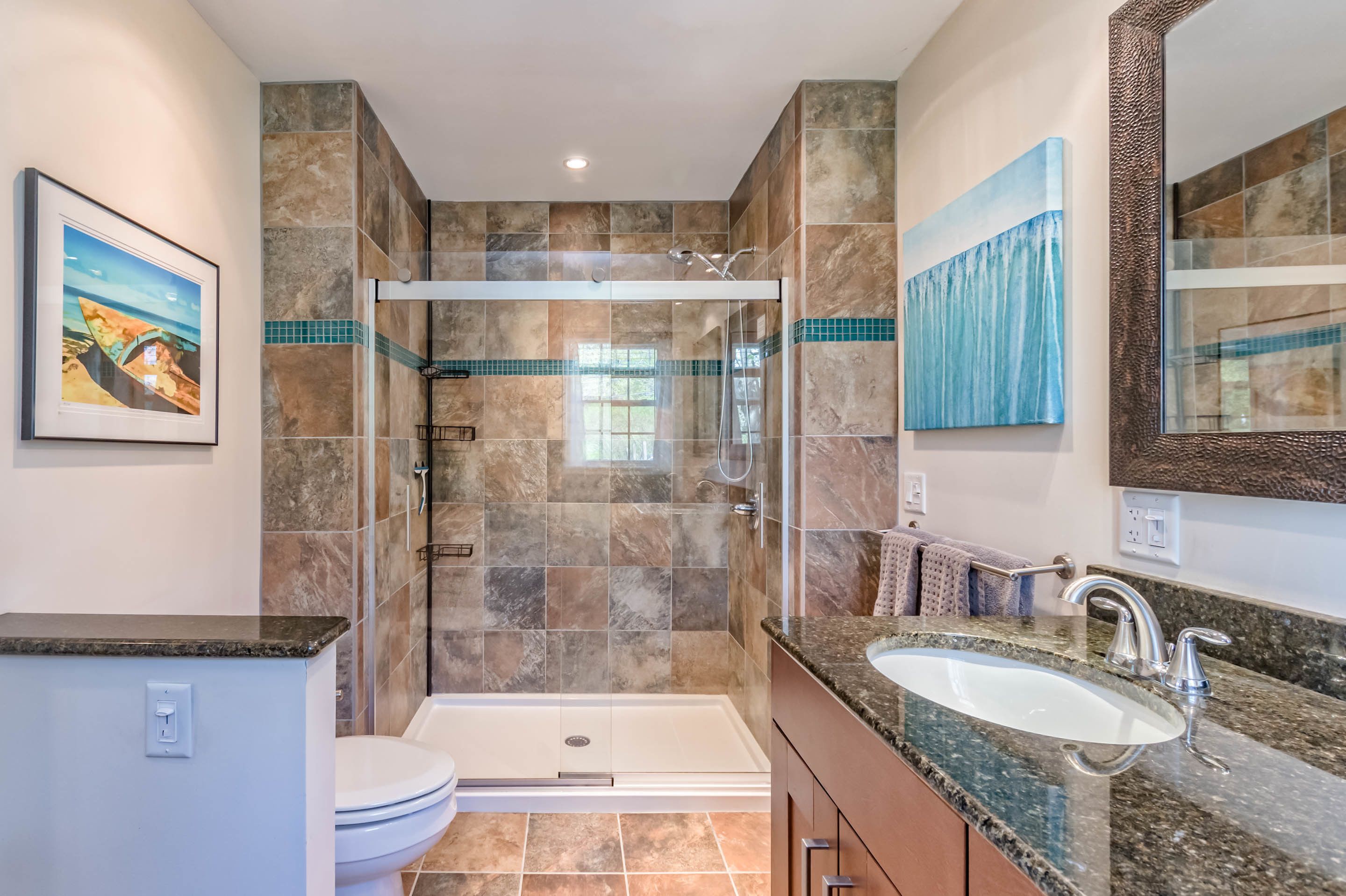 A modern bathroom with a glass-enclosed shower, a bathtub, and a sink with a granite countertop.