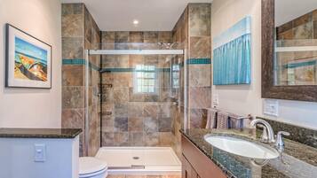 A modern bathroom with a glass-enclosed shower, a bathtub, and a sink with a granite countertop.