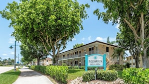 A hotel named 'Aquarius' with a sign, surrounded by trees and a well-maintained lawn.