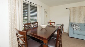 Ein Essbereich mit einem Holztisch und Stühlen, einer Couch und einer Tür mit Fenster.