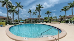 A swimming pool with a 3 FT depth marker, surrounded by palm trees and hotel buildings.