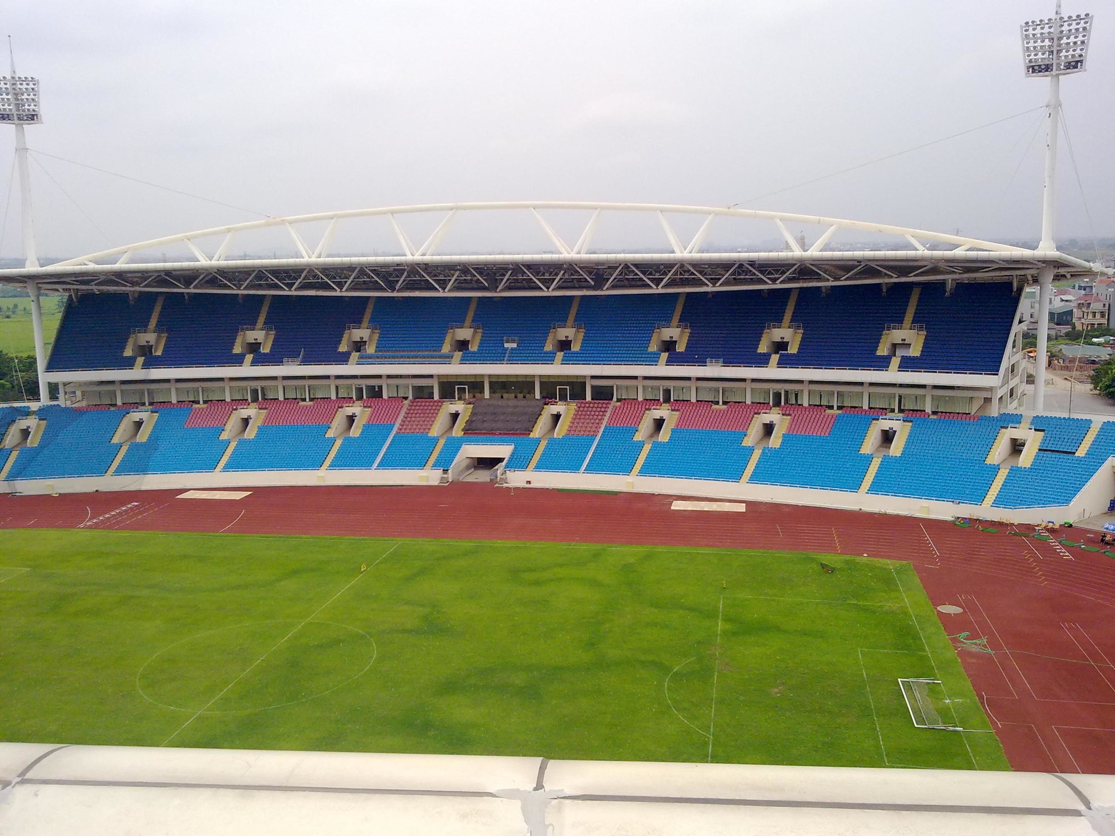 A stadium with blue and red seating, a running track, and floodlights.