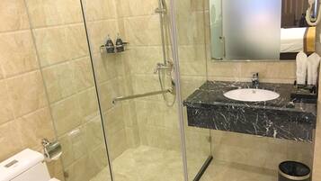 A modern bathroom with a glass-enclosed shower, a marble sink, and a mirror above the sink.