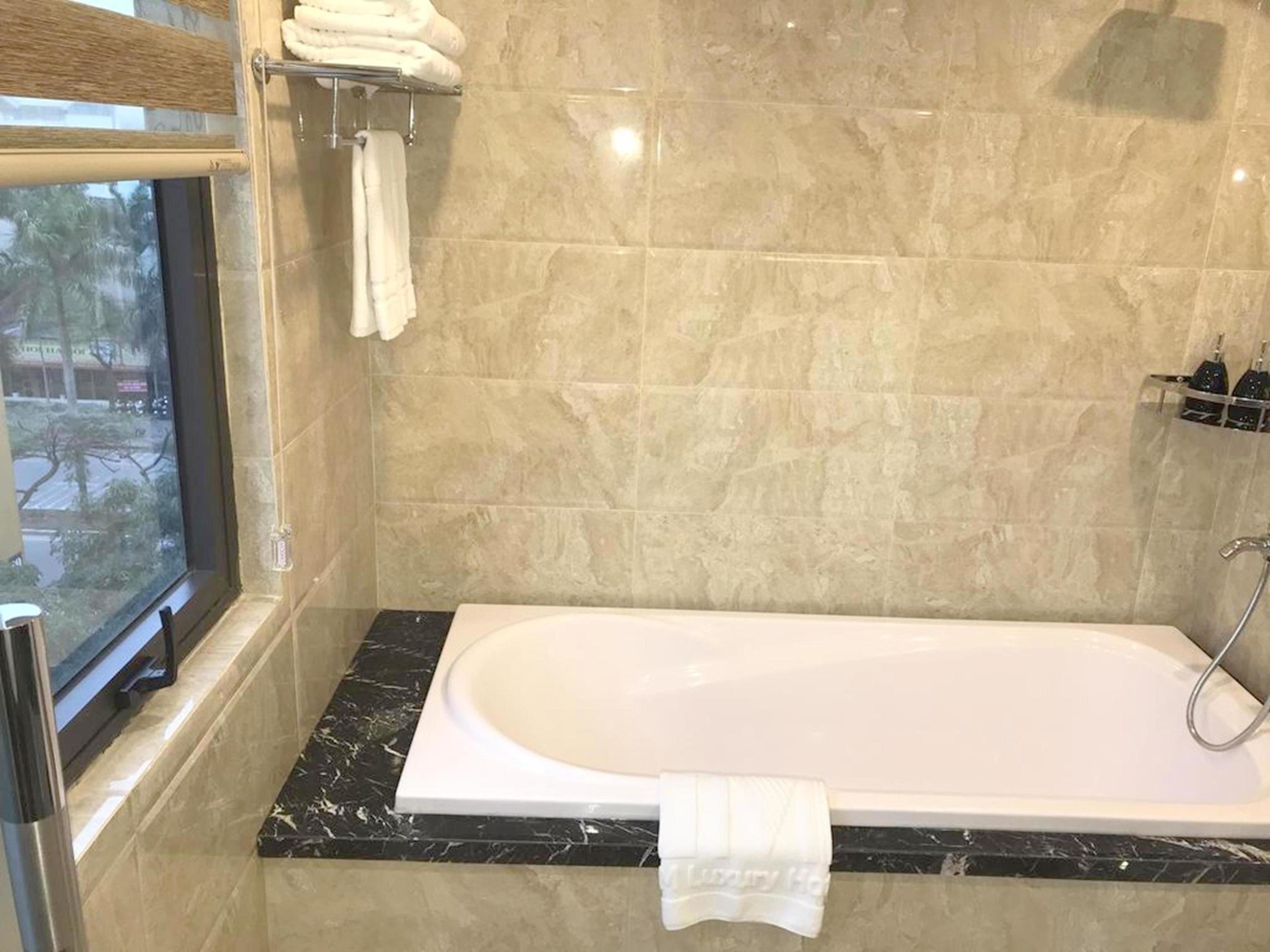 Une salle de bain moderne avec une grande baignoire, des comptoirs en marbre et une fenêtre donnant sur l’extérieur.