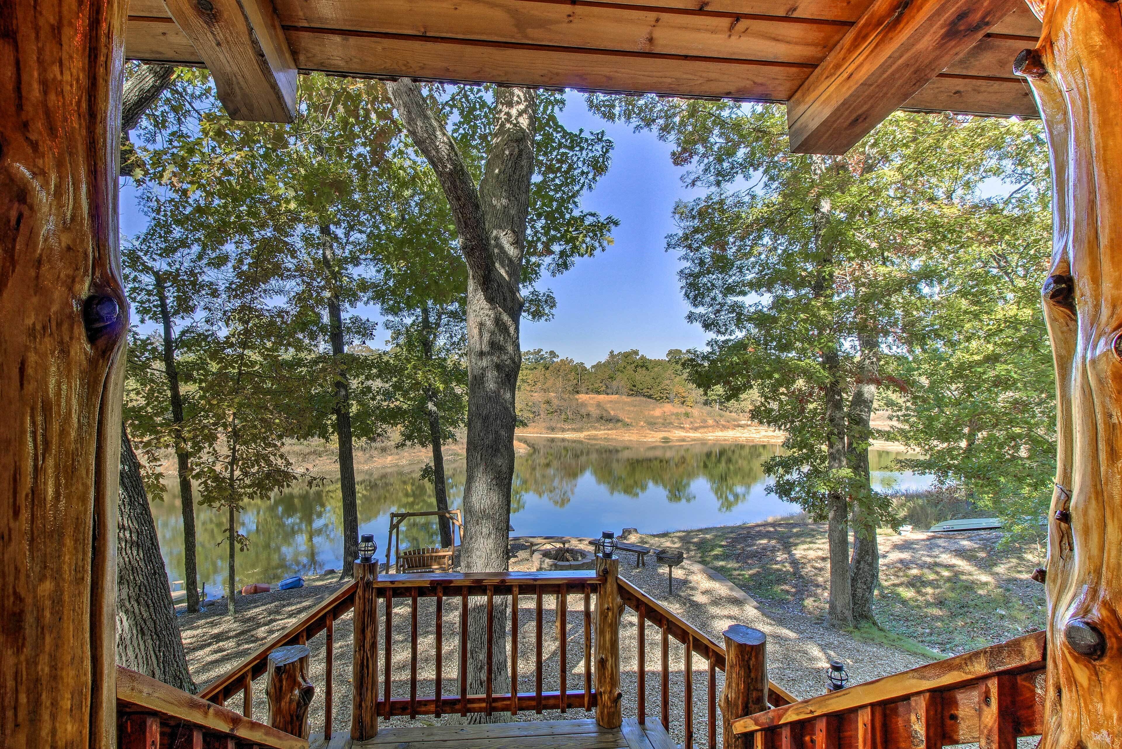 A wooden deck with a view of a lake surrounded by trees.