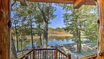 Une terrasse en bois offrant une vue sur un lac entouré d’arbres.