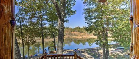 A wooden deck with a view of a lake surrounded by trees.