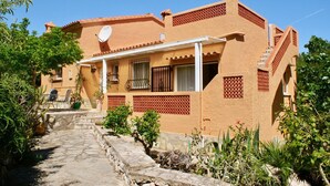A traditional Mediterranean-style building with a stone pathway leading to the entrance, surrounded by greenery. - Rustic villa with pool Marquesa GR (Denia)