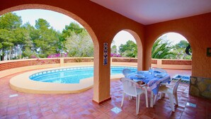 A covered outdoor area with a pool, dining table, and chairs. - Rustic villa with pool Marquesa GR (Denia)